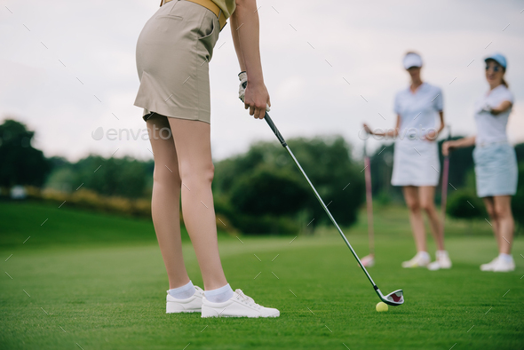 partial view of woman playing golf with friends near by at golf course