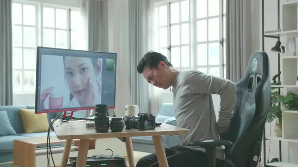 Asian Cameraman Having Backache While Using Desktop Computer For Editing Photo At Home alt