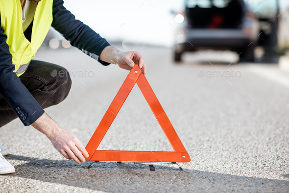 Man putting emergency sign on the road