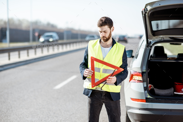 Man with emergency sign on the roadside