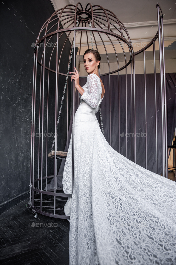 Fashion bride in an iron cage, unhappily looking out from behind bars. Life out of will.