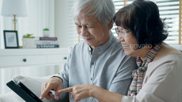 Candid old asian retired couple use tablet computer to transfer money online
