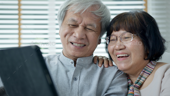 Candid old asian retired couple use tablet computer to transfer money online