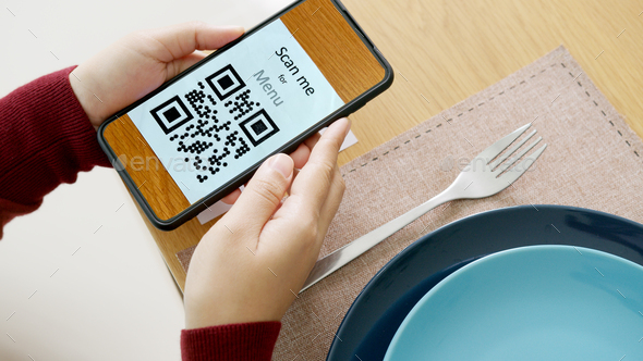 Hand\'s customer scan QR code for online menu service at table in restaurant