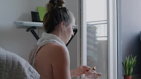Woman  sitting with headphones and sets fire to palo santo before meditation at home alt