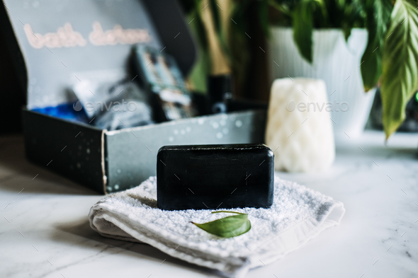 Lifestyle still life with black charcoal soap on beauty box background. Handmade soap with activated
