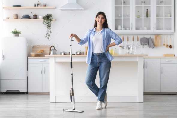 Portrait of cheerful woman cleaning floor with spray mop, posing