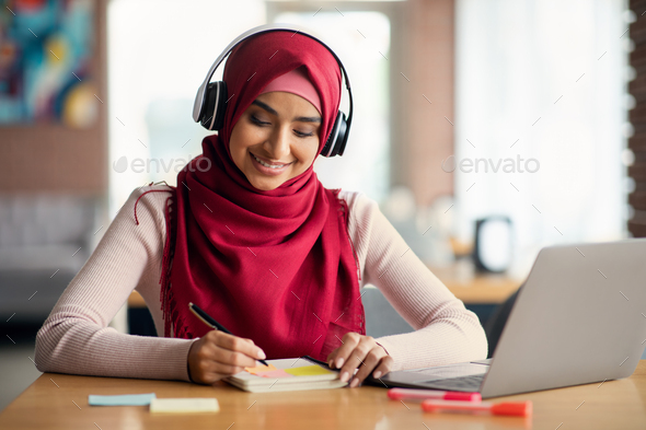 Smiling middle-eastern woman having online training, cafe interior