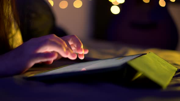 Close up shot of female hand using tablet touching and typing on screen.