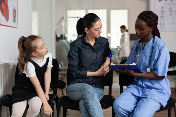 Family discussing medical treatment with african american nurse in hospital - Stock Photo - Images