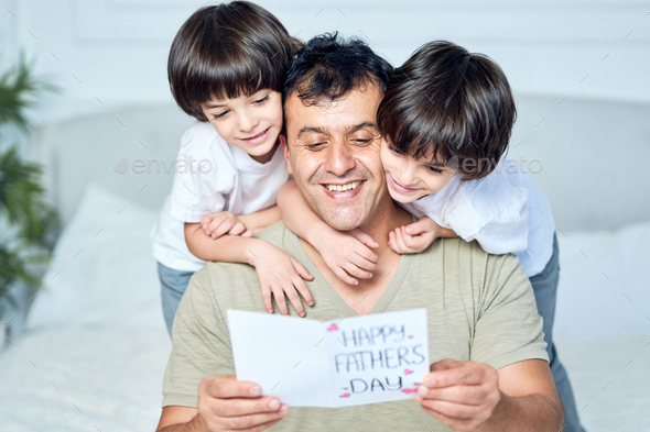 The coolest Dad. Portrait of latin father looking happy while his two little boys embracing their