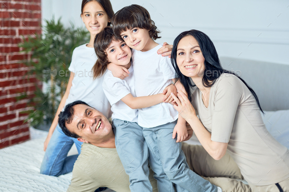 Family time. Portrait of happy latin family, parents and children smiling at camera while spending