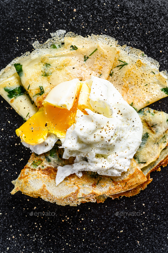 Plate of pancake stuffed with spinach and eggs. Black background. Top