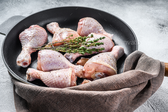 Raw fresh chicken drumsticks with spices in a pan. White background. Top view - Stock Photo - Images