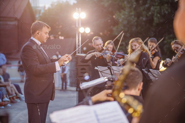 Male conductor directing orchestra performance on the street - Stock Photo - Images
