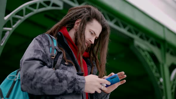 An Attractive Handsome Man with a Beautiful Hairstyle and Beard Using His Modern Smartphone alt