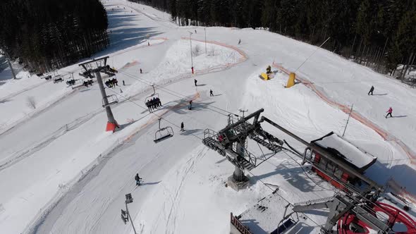Aerial View of Ski Slopes with Skiers Go Down Under Ski Lifts on Ski Resort alt