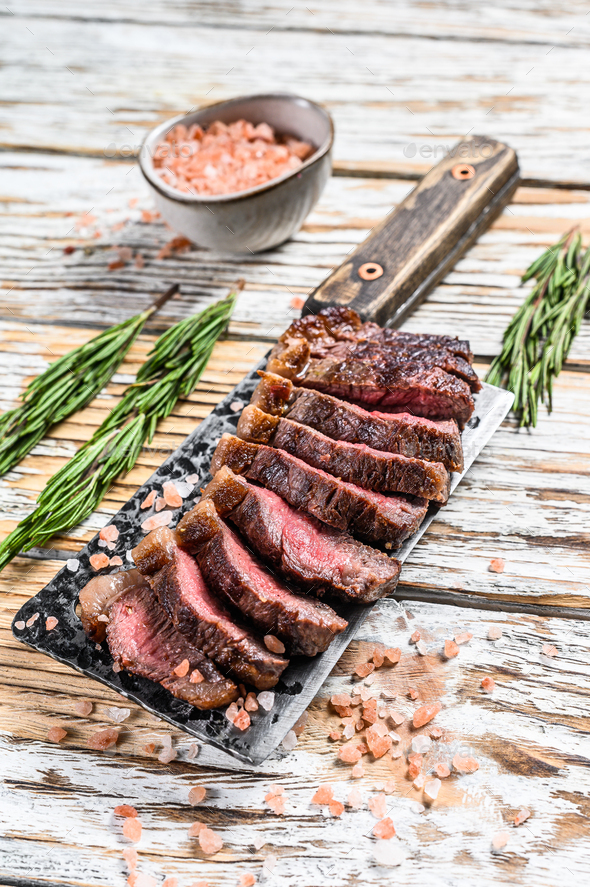 Grilled top sirloin cap or picanha steak on a meat cleaver with herbs. Stock Photo by composterbox
