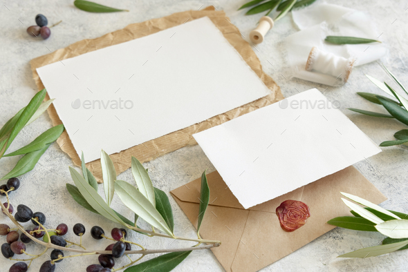 Wedding cards laying on marble table with olive tree branches