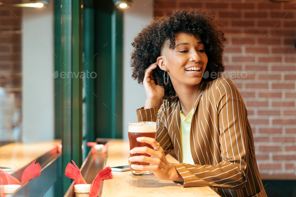 Black woman with beer in pub - Stock Photo - Images