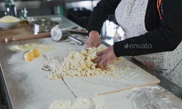 Woman kneading dough for fresh made gnocchi inside pasta factory
