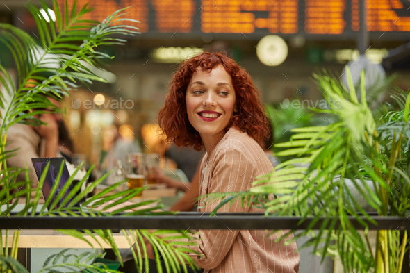 Cheerful young woman working on laptop in cafe - Stock Photo - Images