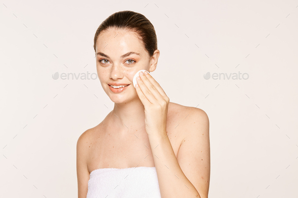 Peaceful female applying toner on radiant face with sponge
