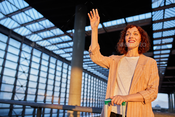 Young female traveler waving hand at station - Stock Photo - Images