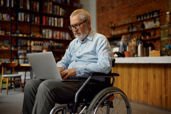 Adult disabled man in wheelchair using laptop - Stock Photo - Images