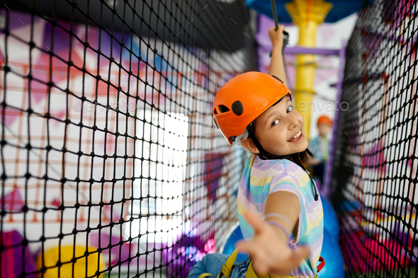 Little girl climbs on the ropes, zip line - Stock Photo - Images