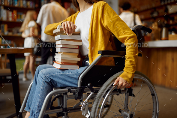 Disabled female student holds stack of books - Stock Photo - Images