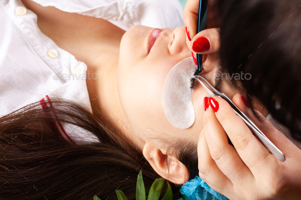 Eyelash extensions in a beauty salon. A young girl lies on a couch