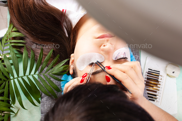 Eyelash extensions in a beauty salon. A young girl lies on a couch
