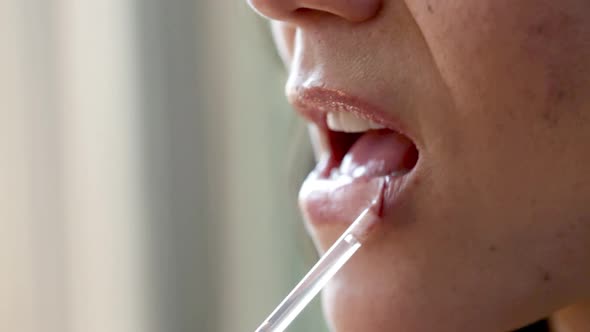 Close up of woman applying lip gloss alt