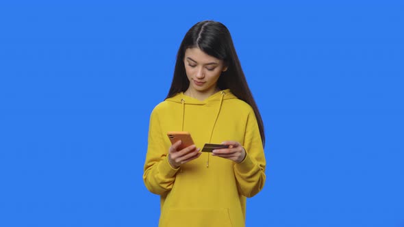 Portrait of Pretty Brunette Makes an Online Purchase Using Credit Card and Phone alt