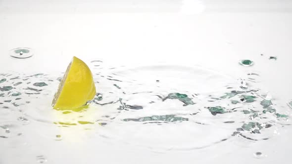 Half a Lemon Drops Into the Water. White Background. Slow Motion alt