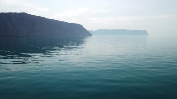 Aerial View From Above on Calm Azure Sea and Volcanic Rocky Shores alt