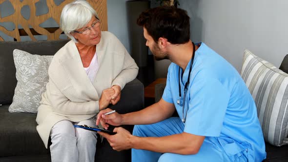 Doctor and senior woman discussing over clipboard alt