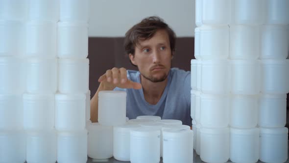 A Man is Sitting in Front of a Wall Made of Plastic Cans alt