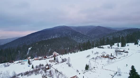 Flying Over the Houses on the Hill Overlooking the Winter Mountains