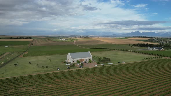 white farmhouse in green vineyard valley of Franschoek South Africa, aerial alt