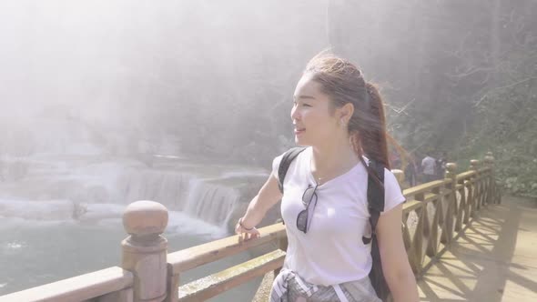 Tourist Woman Walking On Wooden Bridge Near Waterfall alt