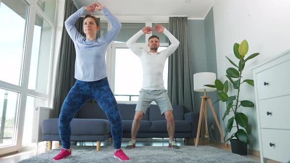 Caucasian Couple is Doing Jumping Jacks Exercise at Home in Cozy Bright Room Slow Motion alt