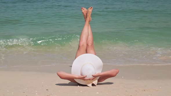 Girl Lies on a Sandy Beach in a Luxury Resort Against the Blue Ocean Surf