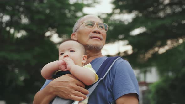Asian Grandfather carrying his Grandson walking at outdoor together.