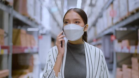 Asian woman business owner wear face mask hand smartphone checking stock