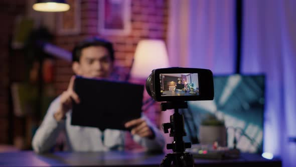 Camera on Tripod Filming Podcast Show with Man Doing Product Review alt