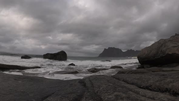 Waves breaking in Norway under dark overcast sky