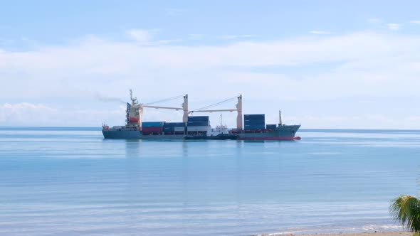 A fully loaded shipping container cargo ship being guided by a tug boat, vessel slowly coming into c alt