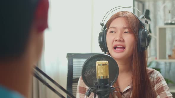 Over Shoulder View Of Asian Man Host Record Podcast Interview Guest Conversation In His Home Studio alt